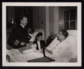 Capt. Ackers visiting wounded, nurse and man in bed also in photo 